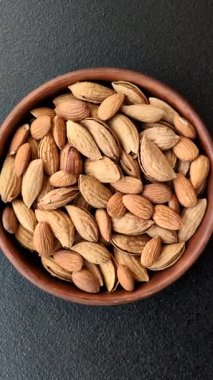 Kavrulmuş ya da çiğ badem fıstığı kabukta koyu beton arka planda.