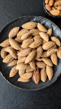 Kavrulmuş ya da çiğ badem fıstığı kabukta koyu beton arka planda.