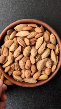 Kavrulmuş ya da çiğ badem fıstığı kabukta koyu beton arka planda.