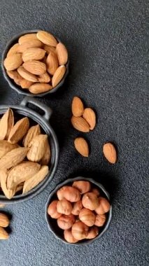 Kavrulmuş ya da çiğ badem fıstığı kabukta koyu beton arka planda.