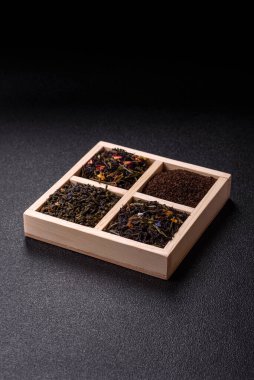 Farklı türde kuru çay, yeşil, siyah, nane, gül ve papatya, kutuda tahta kaşık.