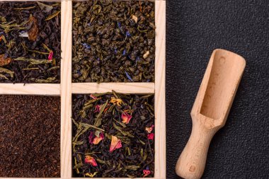 Farklı türde kuru çay, yeşil, siyah, nane, gül ve papatya, kutuda tahta kaşık.
