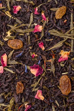 Kuru çay karışımı, koyu beton arka planda siyah, yeşil ve çiçek yaprakları.