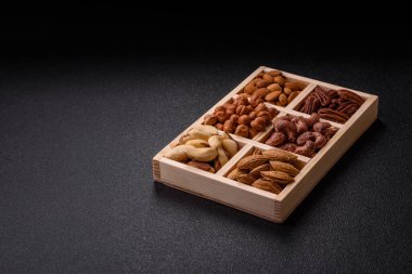 Farklı fındıklı ahşap kutu, fındık, fındık, badem, Brezilya cevizi, ceviz, koyu beton arka planda ceviz.