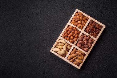 Farklı fındıklı ahşap kutu, fındık, fındık, badem, Brezilya cevizi, ceviz, koyu beton arka planda ceviz.