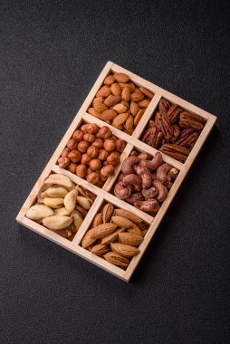 Farklı fındıklı ahşap kutu, fındık, fındık, badem, Brezilya cevizi, ceviz, koyu beton arka planda ceviz.