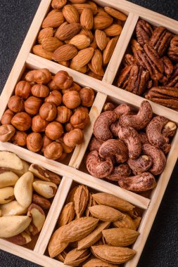 Farklı fındıklı ahşap kutu, fındık, fındık, badem, Brezilya cevizi, ceviz, koyu beton arka planda ceviz.