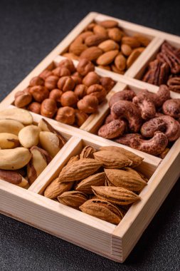 Farklı fındıklı ahşap kutu, fındık, fındık, badem, Brezilya cevizi, ceviz, koyu beton arka planda ceviz.