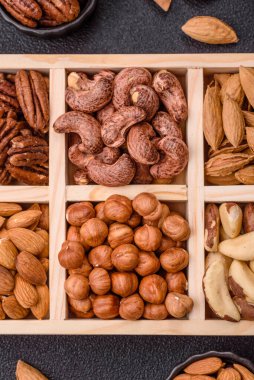 Farklı fındıklı ahşap kutu, fındık, fındık, badem, Brezilya cevizi, ceviz, koyu beton arka planda ceviz.