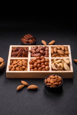 Farklı fındıklı ahşap kutu, fındık, fındık, badem, Brezilya cevizi, ceviz, koyu beton arka planda ceviz.