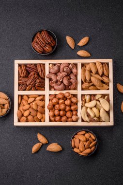 Farklı fındıklı ahşap kutu, fındık, fındık, badem, Brezilya cevizi, ceviz, koyu beton arka planda ceviz.