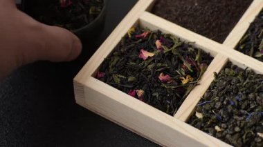 Farklı türde kuru çay, yeşil, siyah, nane, gül ve papatya, kutuda tahta kaşık.