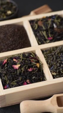 Farklı türde kuru çay, yeşil, siyah, nane, gül ve papatya, kutuda tahta kaşık.
