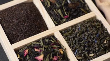 Farklı türde kuru çay, yeşil, siyah, nane, gül ve papatya, kutuda tahta kaşık.