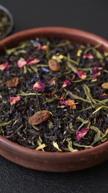 Kuru çay karışımı, koyu beton arka planda siyah, yeşil ve çiçek yaprakları.