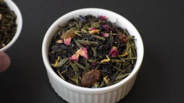 Kuru çay karışımı, koyu beton arka planda siyah, yeşil ve çiçek yaprakları.