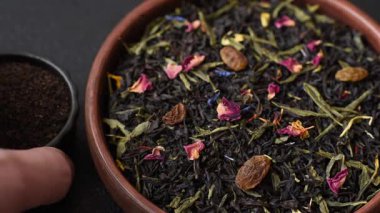 Kuru çay karışımı, koyu beton arka planda siyah, yeşil ve çiçek yaprakları.