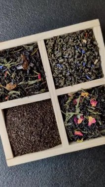 Farklı türde kuru çay, yeşil, siyah, nane, gül ve papatya, kutuda tahta kaşık.