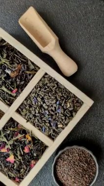 Farklı türde kuru çay, yeşil, siyah, nane, gül ve papatya, kutuda tahta kaşık.