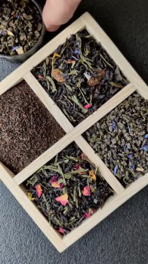 Farklı türde kuru çay, yeşil, siyah, nane, gül ve papatya, kutuda tahta kaşık.