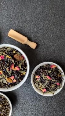 Kuru çay karışımı, koyu beton arka planda siyah, yeşil ve çiçek yaprakları.