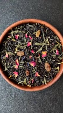 Kuru çay karışımı, koyu beton arka planda siyah, yeşil ve çiçek yaprakları.