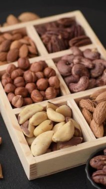 Farklı fındıklı ahşap kutu, fındık, fındık, badem, Brezilya cevizi, ceviz, koyu beton arka planda ceviz.
