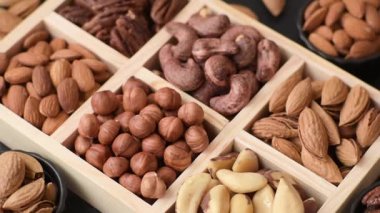 Farklı fındıklı ahşap kutu, fındık, fındık, badem, Brezilya cevizi, ceviz, koyu beton arka planda ceviz.