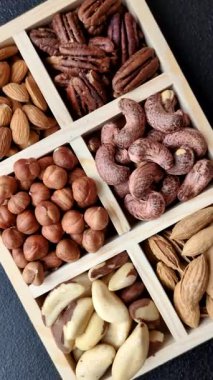 Farklı fındıklı ahşap kutu, fındık, fındık, badem, Brezilya cevizi, ceviz, koyu beton arka planda ceviz.