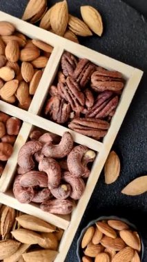 Farklı fındıklı ahşap kutu, fındık, fındık, badem, Brezilya cevizi, ceviz, koyu beton arka planda ceviz.