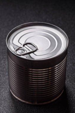 Koyu beton arka planda konserve yiyecekli metal silindirik kutu.
