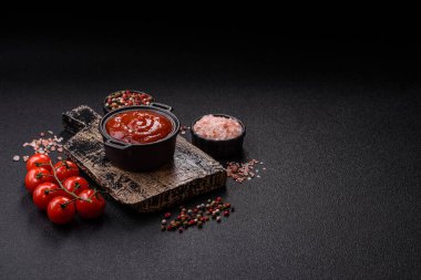 Koyu beton zemin üzerinde seramik sos teknesinde tuz ve baharatlı kırmızı sos ya da ketçap.