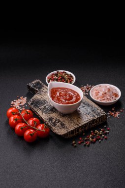 Koyu beton zemin üzerinde seramik sos teknesinde tuz ve baharatlı kırmızı sos ya da ketçap.