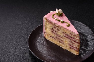 Koyu beton arka planda çilek aromalı pembe katmanlı bir pasta.