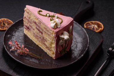 Koyu beton arka planda çilek aromalı pembe katmanlı bir pasta.