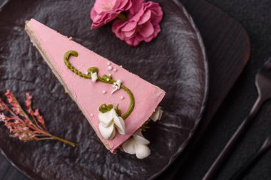 Koyu beton arka planda çilek aromalı pembe katmanlı bir pasta.