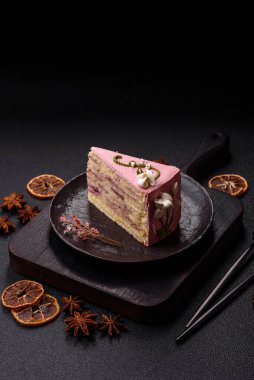 Koyu beton arka planda çilek aromalı pembe katmanlı bir pasta.