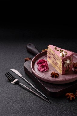 Koyu beton arka planda çilek aromalı pembe katmanlı bir pasta.