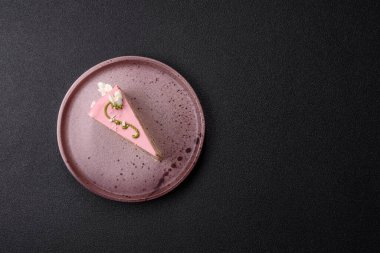 Koyu beton arka planda çilek aromalı pembe katmanlı bir pasta.