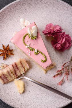 Koyu beton arka planda çilek aromalı pembe katmanlı bir pasta.