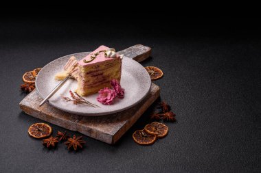 Koyu beton arka planda çilek aromalı pembe katmanlı bir pasta.