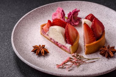 Çilek parçalı yuvarlak tatlı tart ve koyu beton arka planda krema