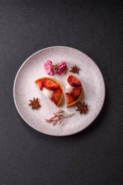 Çilek parçalı yuvarlak tatlı tart ve koyu beton arka planda krema
