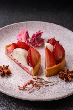 Çilek parçalı yuvarlak tatlı tart ve koyu beton arka planda krema