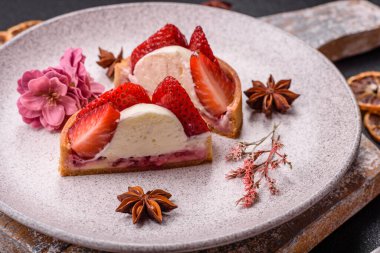 Çilek parçalı yuvarlak tatlı tart ve koyu beton arka planda krema