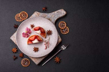 Çilek parçalı yuvarlak tatlı tart ve koyu beton arka planda krema