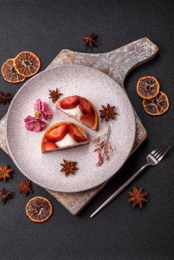 Çilek parçalı yuvarlak tatlı tart ve koyu beton arka planda krema