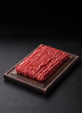 Koyu beton arka planda çiğ et veya tuzlu ve baharatlı domuz eti.