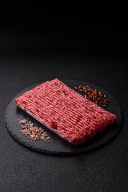 Koyu beton arka planda çiğ et veya tuzlu ve baharatlı domuz eti.