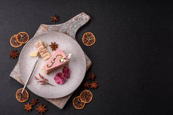 Koyu beton arka planda çilek aromalı pembe katmanlı bir pasta.
